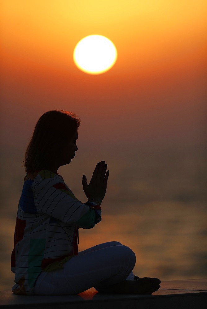 Woman practising yoga pose and meditation at sunset as concept for silence and relaxation, United Arab Emirates, Middle East