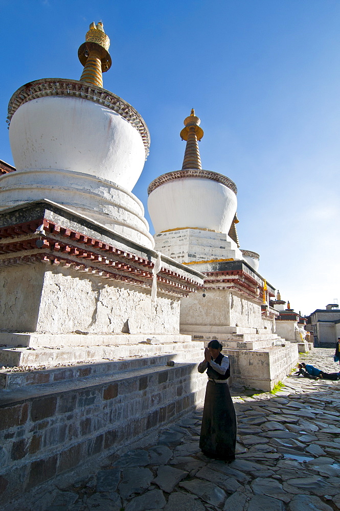 Pilgrim in front of the white stupas at the Tashilumpo monastery, Shigatse, Tibet Autonomous Region, China, Asia