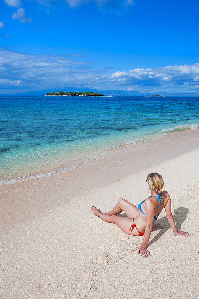 Woman sitting on a the white sand beach of Beachcomber Island, Mamanucas Islands, Fiji, South Pacific, Pacific