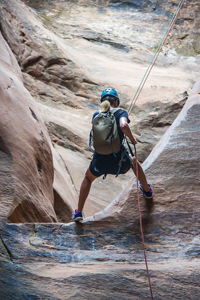 Woman rapelling down in slot canyon, canyoneering, Moab, Utah, United States of America, North America