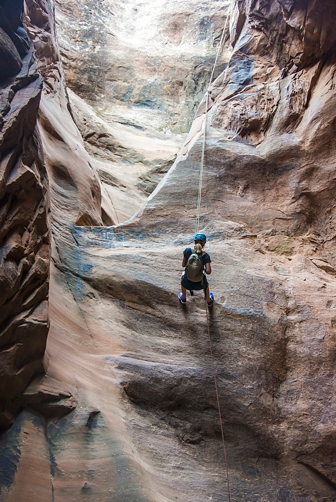 Woman rapelling down in slot canyon, canyoneering, Moab, Utah, United States of America, North America