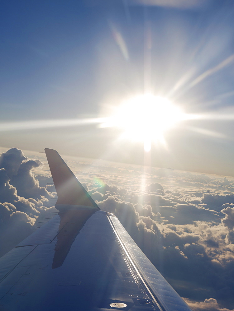 Airplane wing and sun burst over clouds while in flight en route to Houston, Texas, United States of America, North America