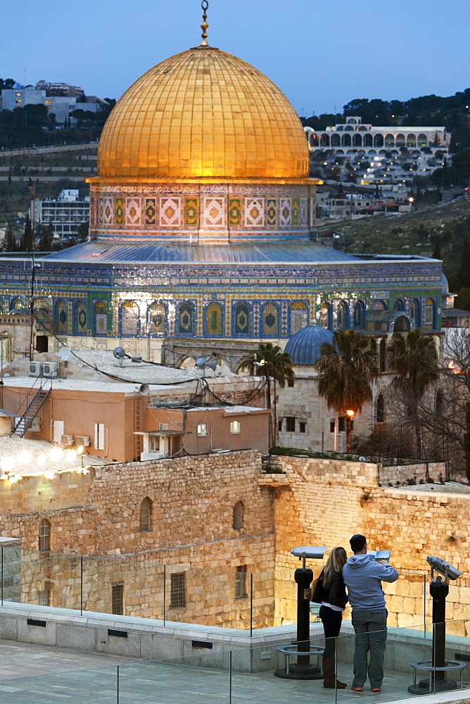 Couple looking over to the Dome of the Rock and the Wailing Wall at dusk, Jerusalem, Israel, Middle East