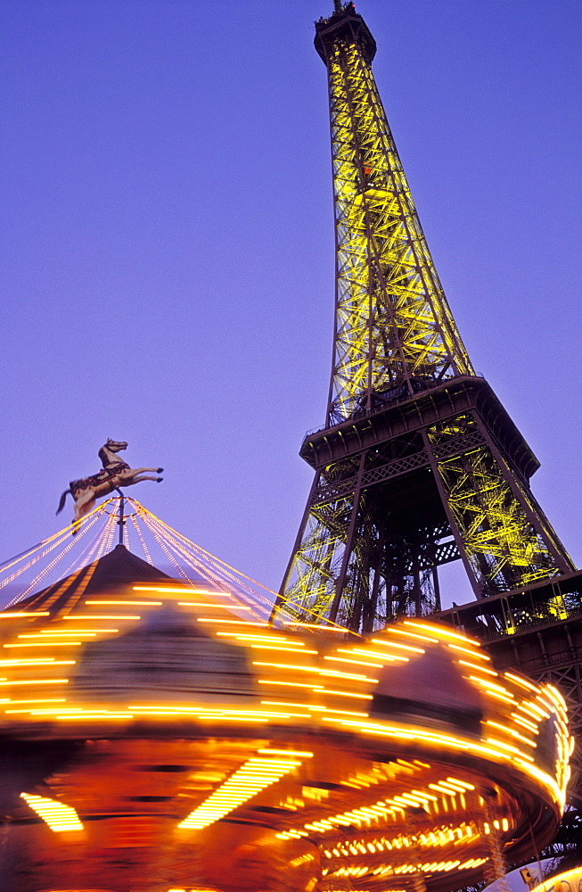 The Eiffel Tower illuminated at night with a carousel spinning, Paris, France, Europe