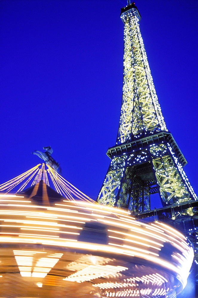 The Eiffel Tower illuminated at night with a carousel spinning, Paris, France, Europe