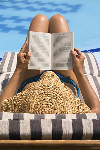 Woman reading by swimming pool