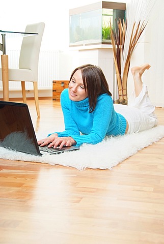 Woman on sheepskin rug using laptop at home