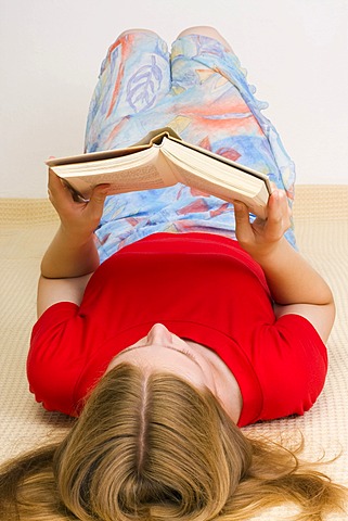 Girl, 17 years, reading a book, lying on the floor