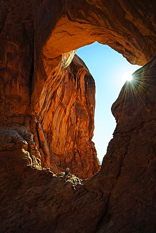 Hiker relaxing under the Double Arch, stone arches of red sandstone formed by erosion, Arches-Nationalpark, near Moab, Utah, United States