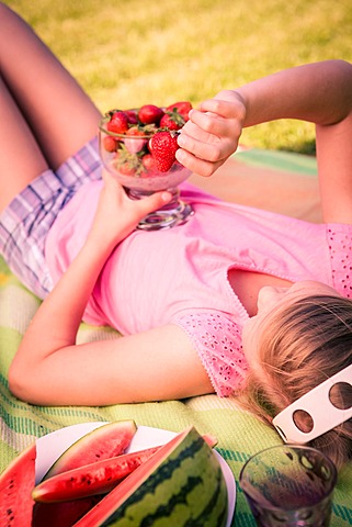 Girl eating strawberries in the garden