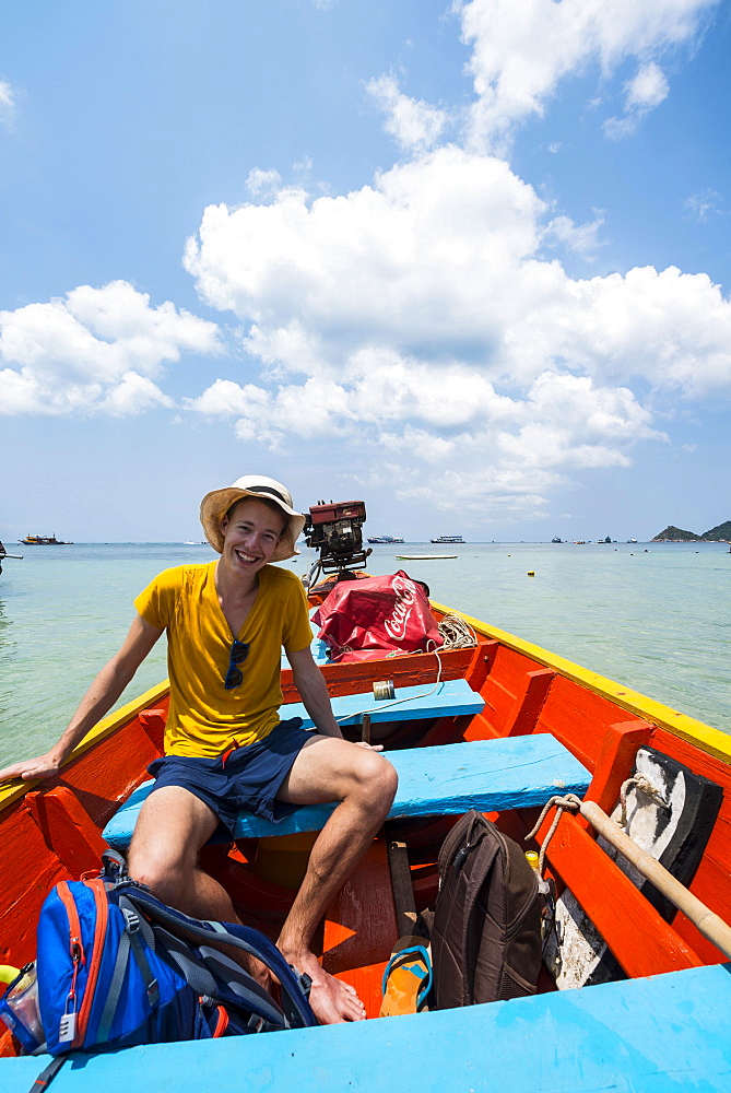 Young man sitting in longtail boat, turquoise sea, Koh Tao, Gulf of Thailand, Thailand, Asia