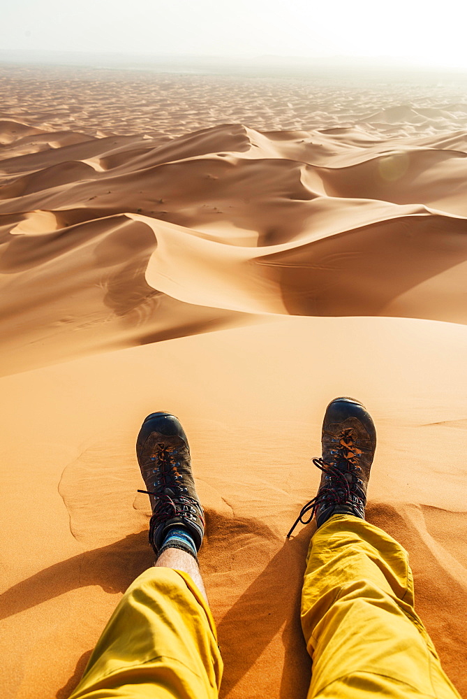 Legs with hiking boots in the sand, sand dune, desert, Erg Chebbi, Merzouga, Sahara, Morocco, Africa