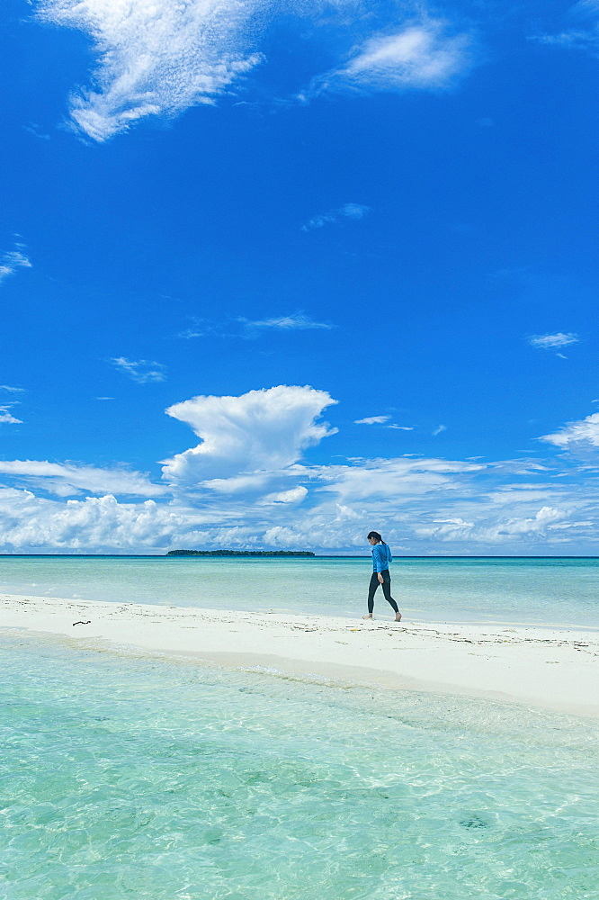 Tourist walking on a sand strip at low tide, Rock Islands, Palau, Oceania