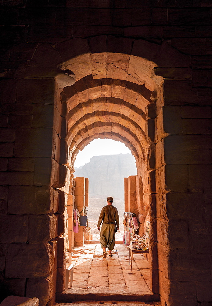 Tourist at the entrance to one of the royal tombs, rock carved mausoleum, Nabataean city of Petra, near Wadi Musa, Jordan, Asia