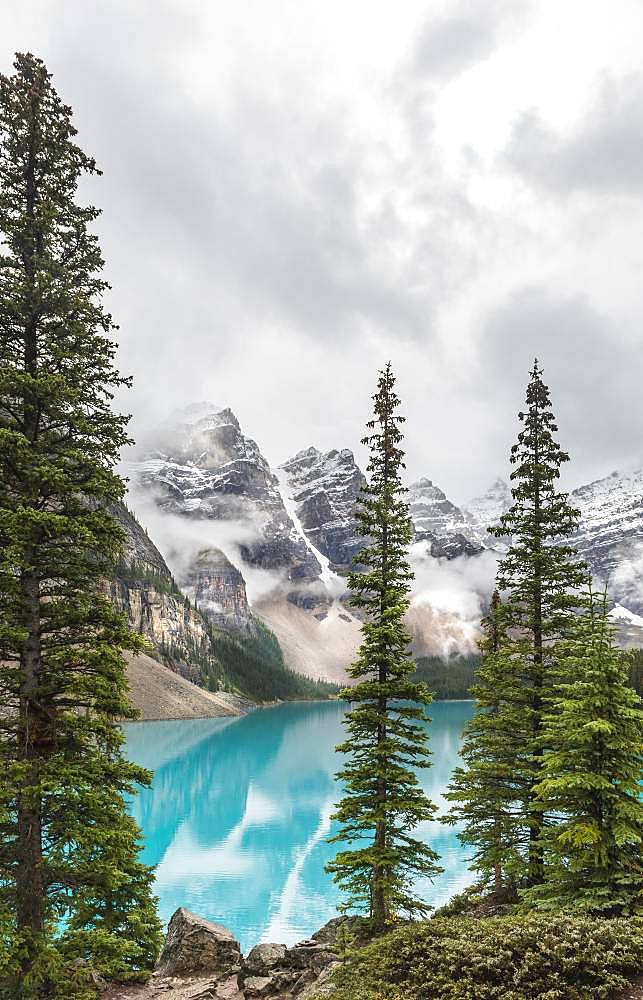 Clouds hanging between the mountain peaks, reflection in turquoise glacial lake, Moraine Lake, Valley of the Ten Peaks, Rocky Mountains, Banff National Park, Alberta Province, Canada, North America