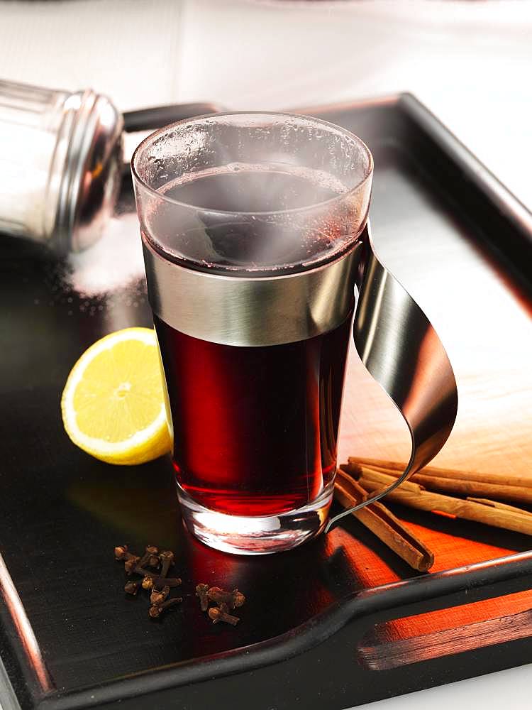 Hot mulled wine on dark tray, lemon, cinnamon sticks, cloves and sugar, Germany, Europe