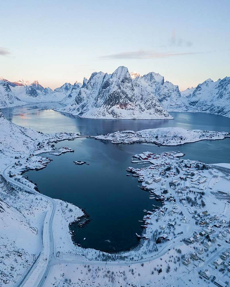 Snow-covered mountains at the fjord with village Reine, drone shot, Lofoten, Norway, Europe