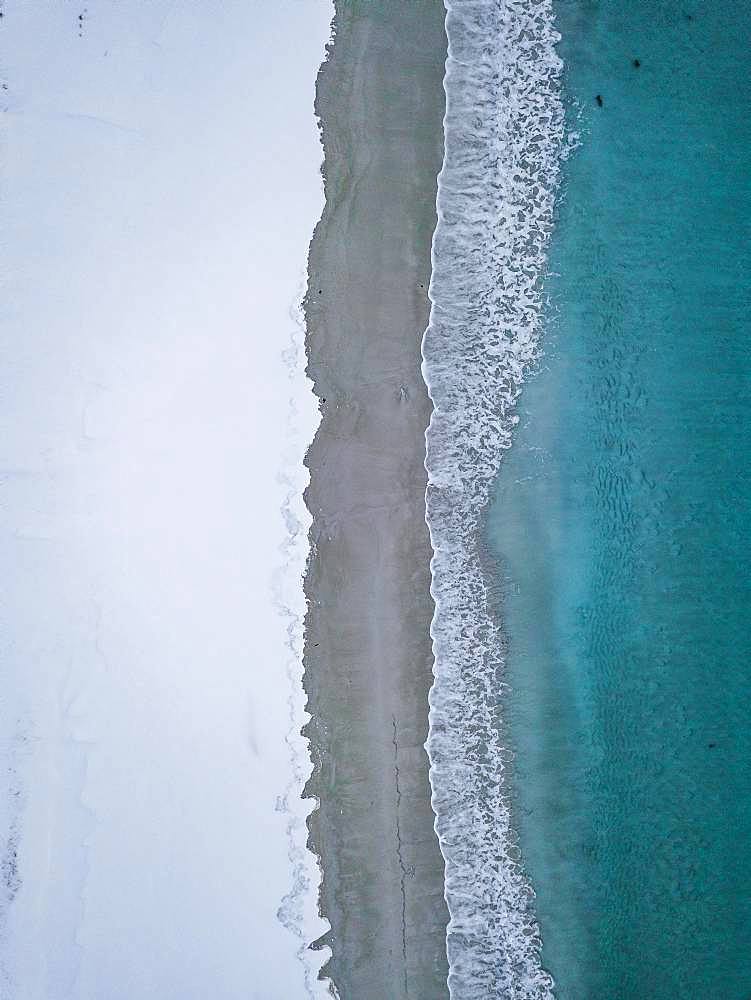 Haukland beach from above, turquoise sea water borders on snow surface, drone shot, Lofoten, Norway, Europe