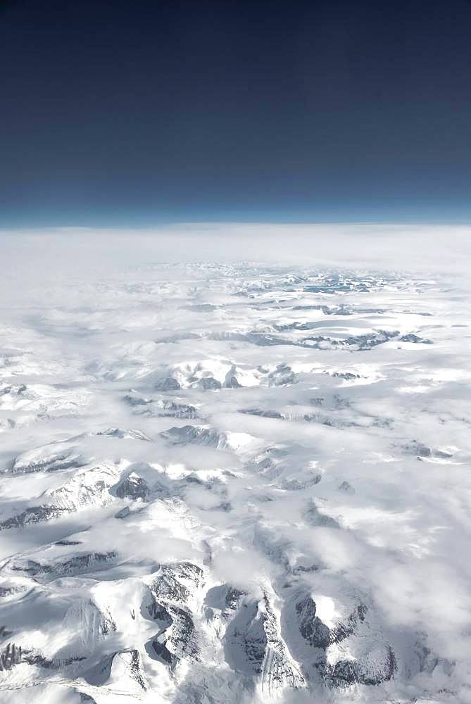 View from the plane to snow-covered mountainous landscape, horizon, bird's eye view, Greenland, North America