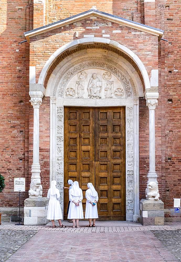 Nuns contemplate the Porta Santa of the Abbey Church of San Silvestro, Romanesque, Nonantola, Province of Modena, Emilia-Romagna, Italy, Europe