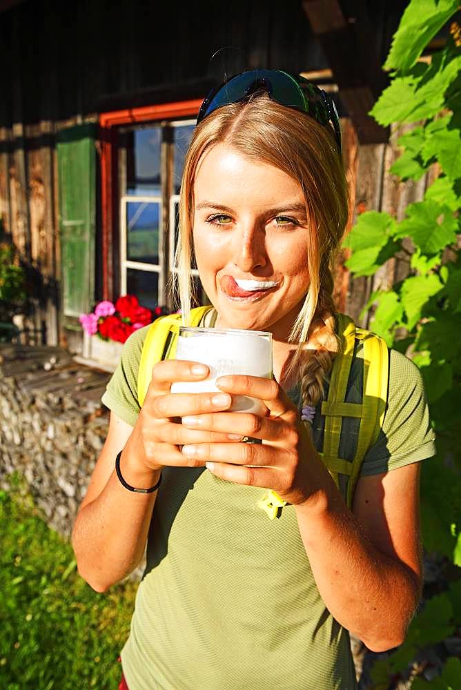 Young female hiker drinks buttermilk at the Kraftalm, Hohe Salve, Itter, Kitzbuehel Alps, Tyrol, Austria, Europe