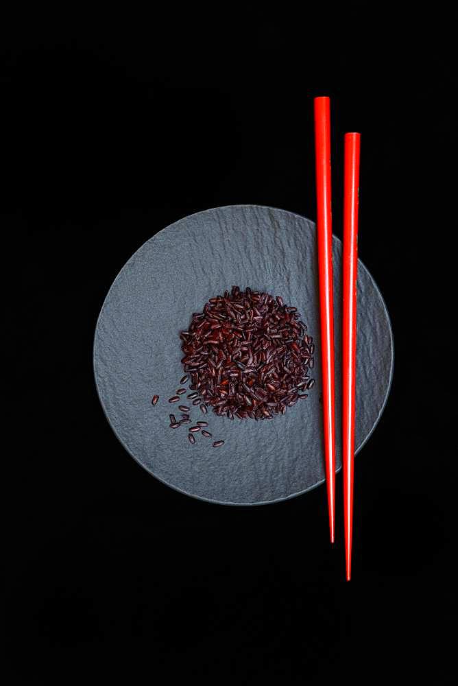 Black rice with red chopsticks on plate, cooked, Germany, Europe