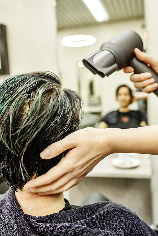 Hairdresser in a hairdressing salon blow-drying the dyed hair of a customer, Cologne, North Rhine-Westphalia, Germany, Europe