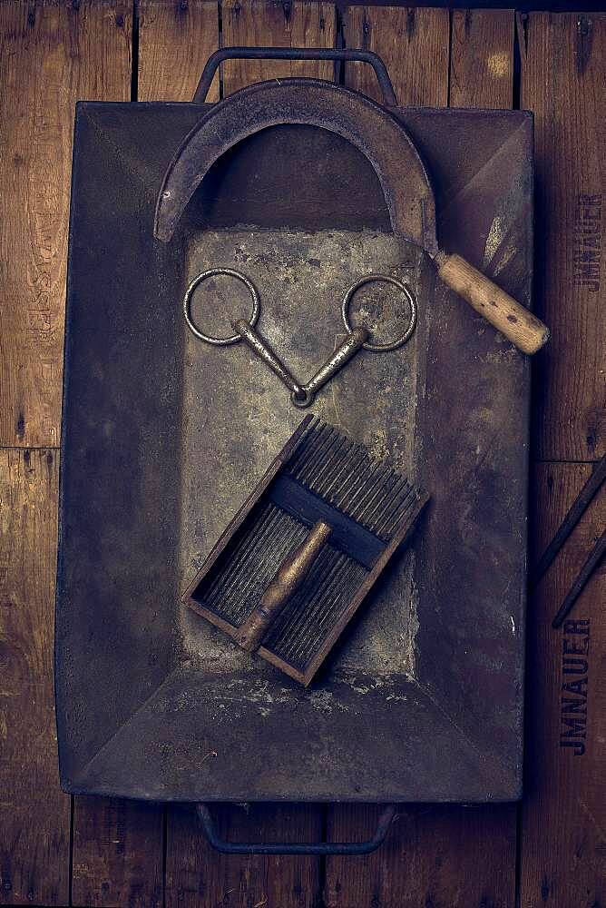 Rural tools, sickle, snaffle, blueberry grater, in an embers tub