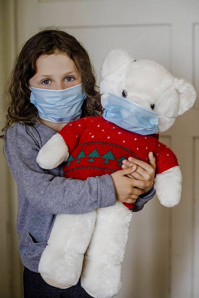 Girl and teddy bear with mouth mask