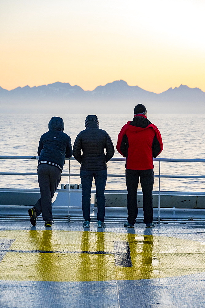 Passengers looking over the ocean, evening mood on the ferry in front of silhouette of mountains, Lofoten, Nordland, Norway, Europe