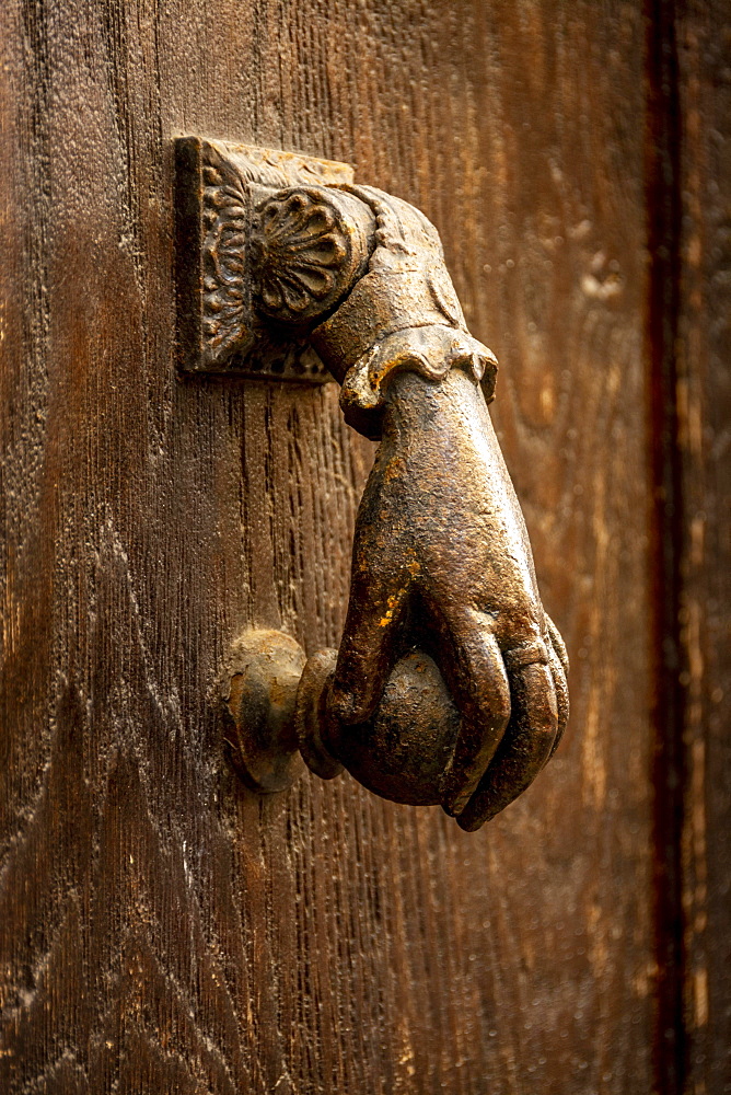 Knocker shaped like a hand on a wooden door, France, Europe