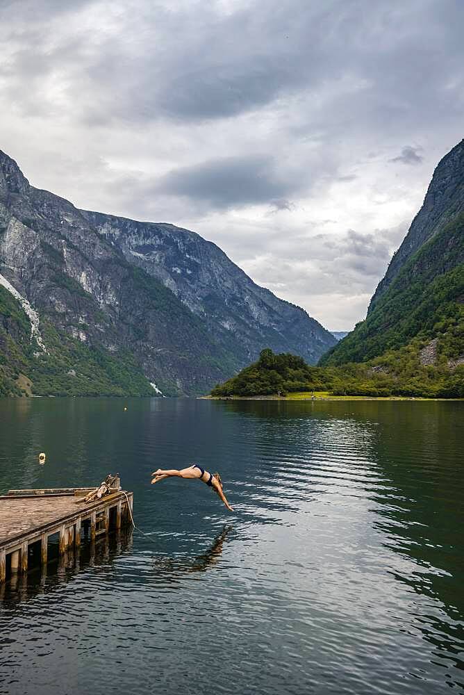 Woman jumping into the water, Naeroyfjord, Aurland, Sogn og Fjordane, Norway, Europe