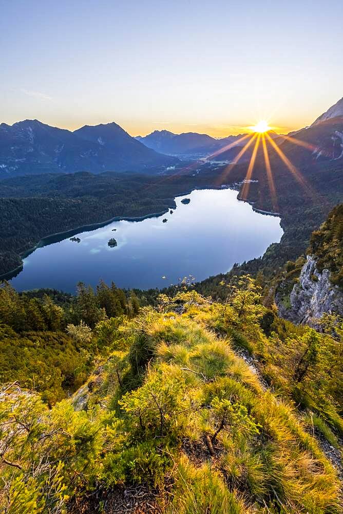 Eibsee lake at sunrise, sun shining over Bavarian alpine foothills, right Zugspitze, Wetterstein mountains near Grainau, Upper Bavaria, Bavaria, Germany, Europe