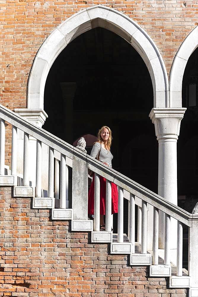 Young woman walking down a staircase, Mercato di Rialto, Venice, Veneto, Italy, Europe