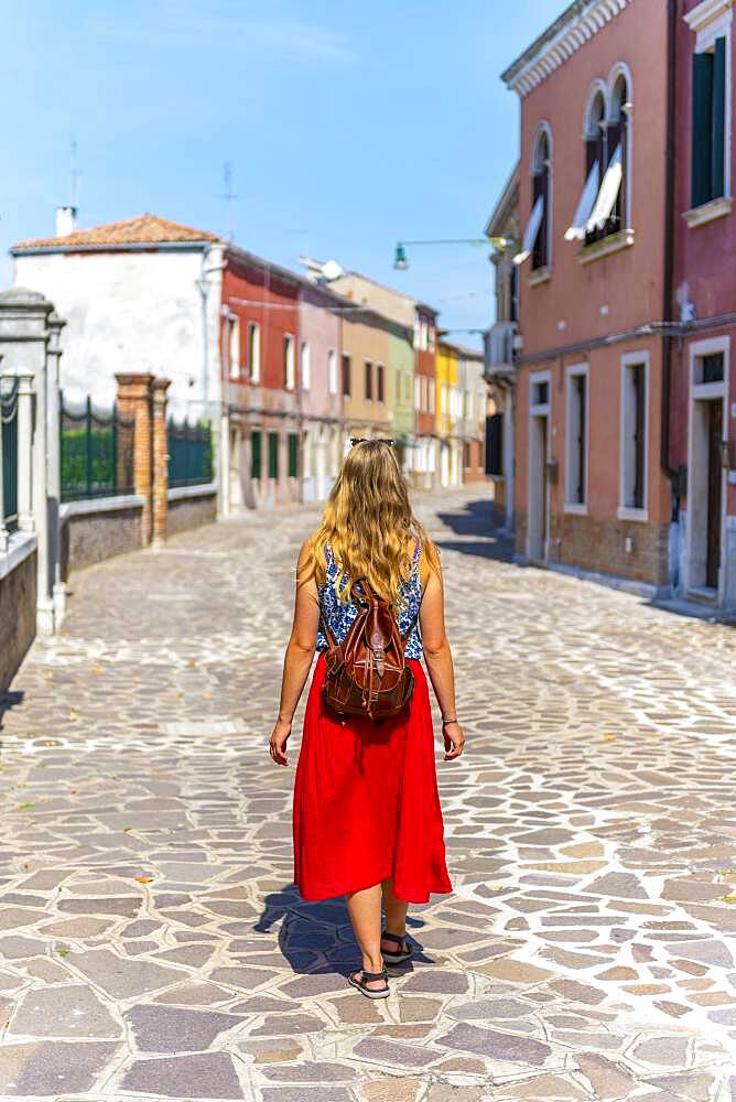 Young woman in front of colorful houses, colorful house facades, Burano Island, Venice, Veneto, Italy, Europe