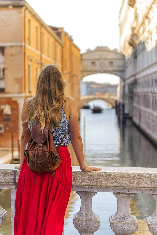 Young woman with red skirt, tourist on a bridge over the Rio di Palazzo, behind Bridge of Sighs, Venice, Veneto, Italy, Europe