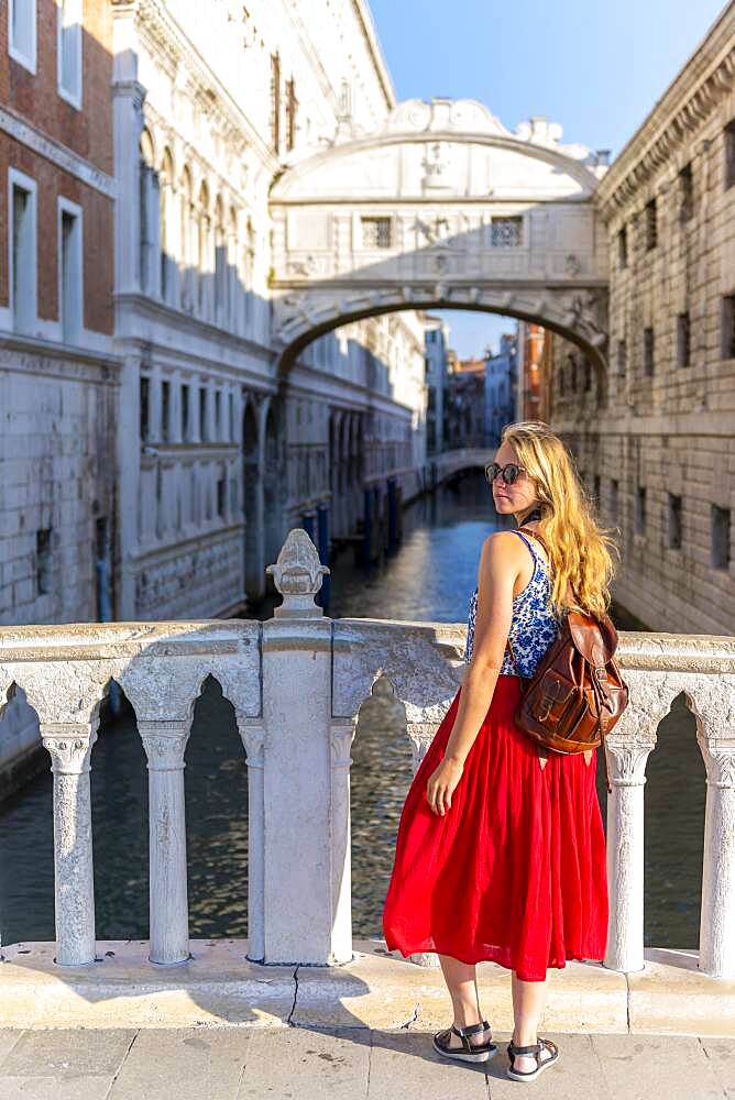 Young woman with red skirt, tourist on a bridge over the Rio di Palazzo, behind Bridge of Sighs, Venice, Veneto, Italy, Europe