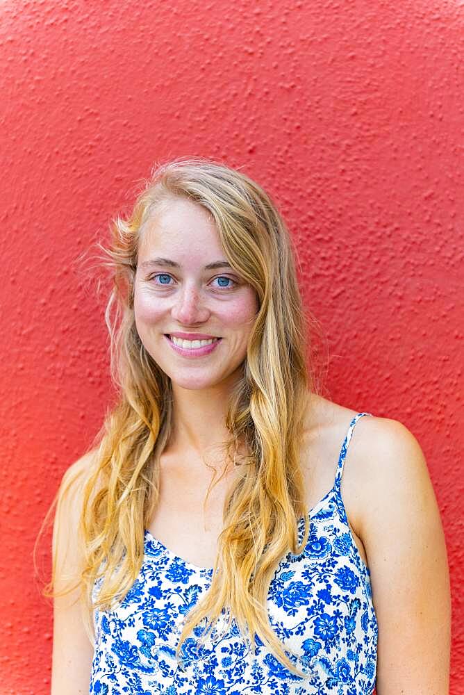 Portrait of a Young Woman in Front of a Red Wall, Burano Island, Venice, Veneto, Italy, Europe