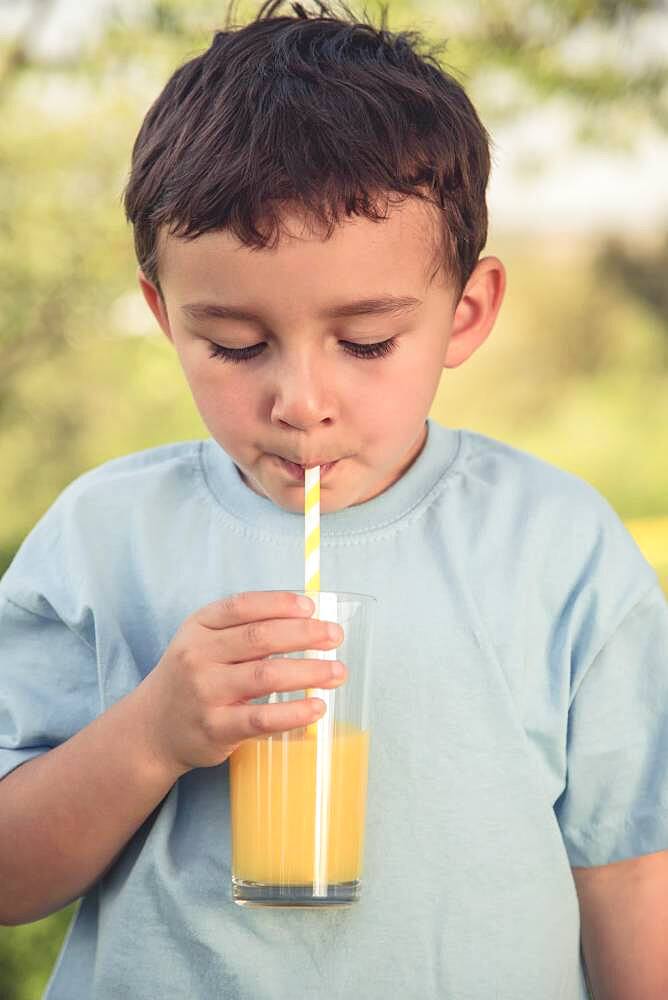 Child little boy drinking orange juice drinking vintage look outside glass, germany