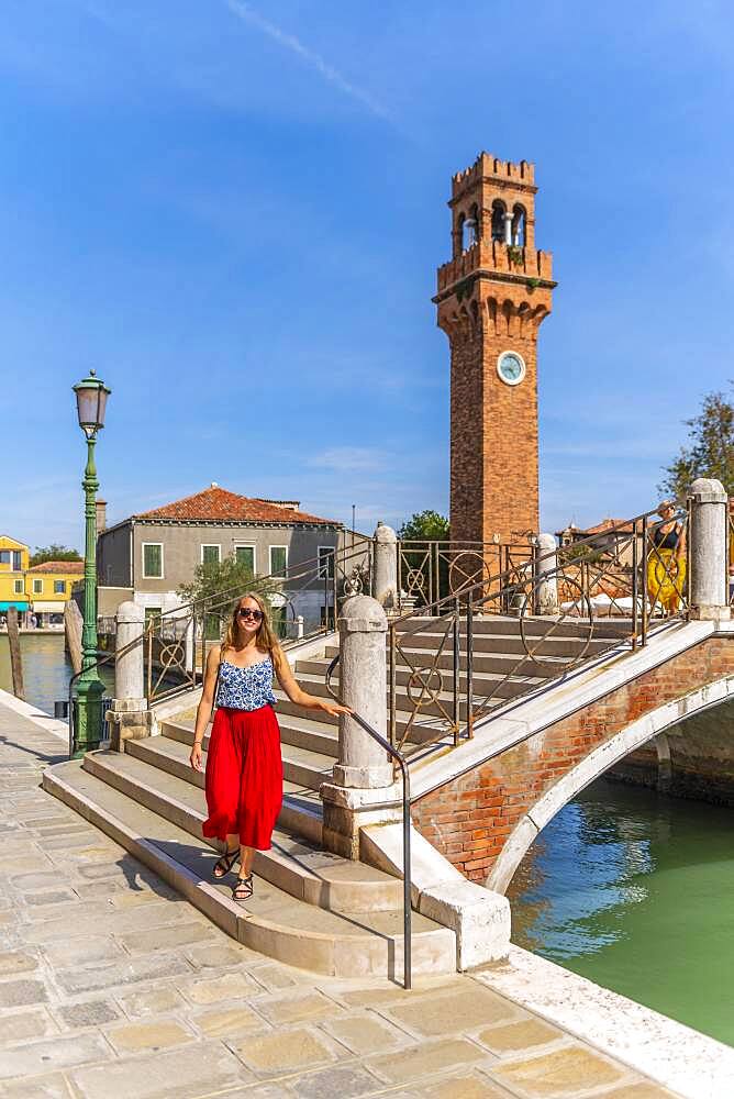 Young woman at a canal, houses and boats at the canal Rio del Vetrai, bell tower St. Stefano, Murano, Venice, Veneto, Italy, Europe