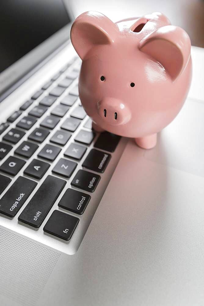 Piggy bank resting on laptop computer keyboard