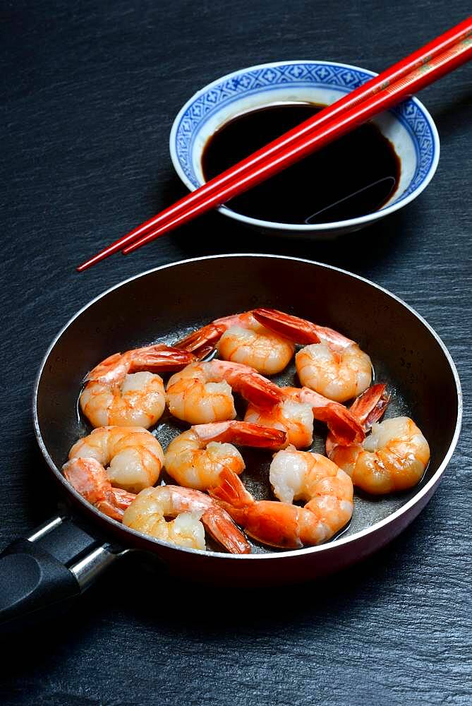 Fried prawns in pan and small bowl with soy sauce, Germany, Europe