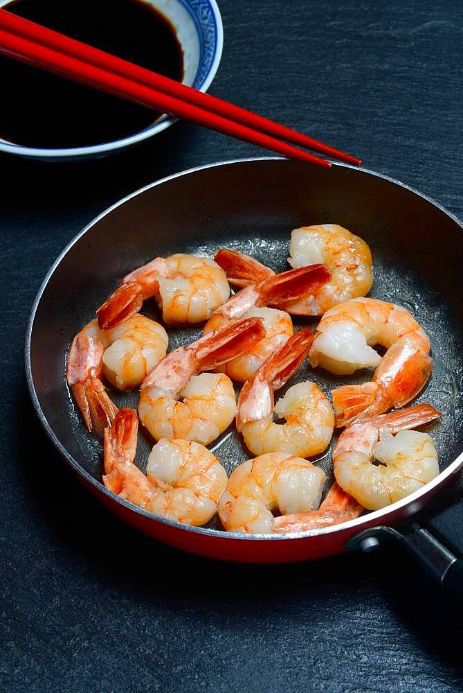 Fried prawns in pan and small bowl with soy sauce, Germany, Europe