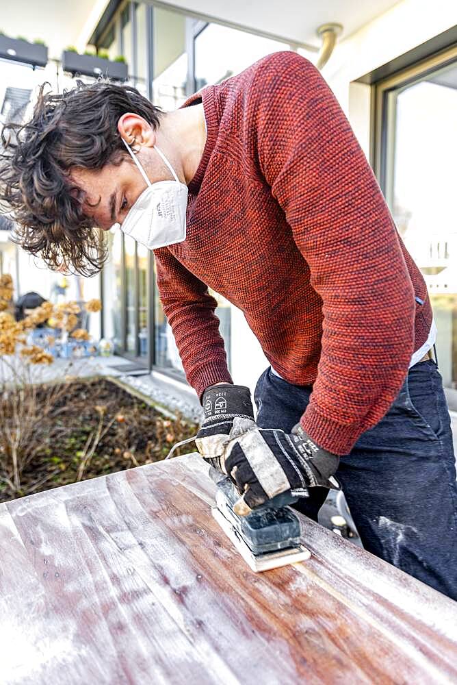 Young man doing DIY, grinding table with a grinder