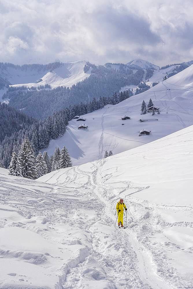 Ski tourers, young man on ski tour to Taubenstein, snowy mountains and huts, Mangfall mountains, Bavarian Prealps, Upper Bavaria, Bavaria, Germany, Europe