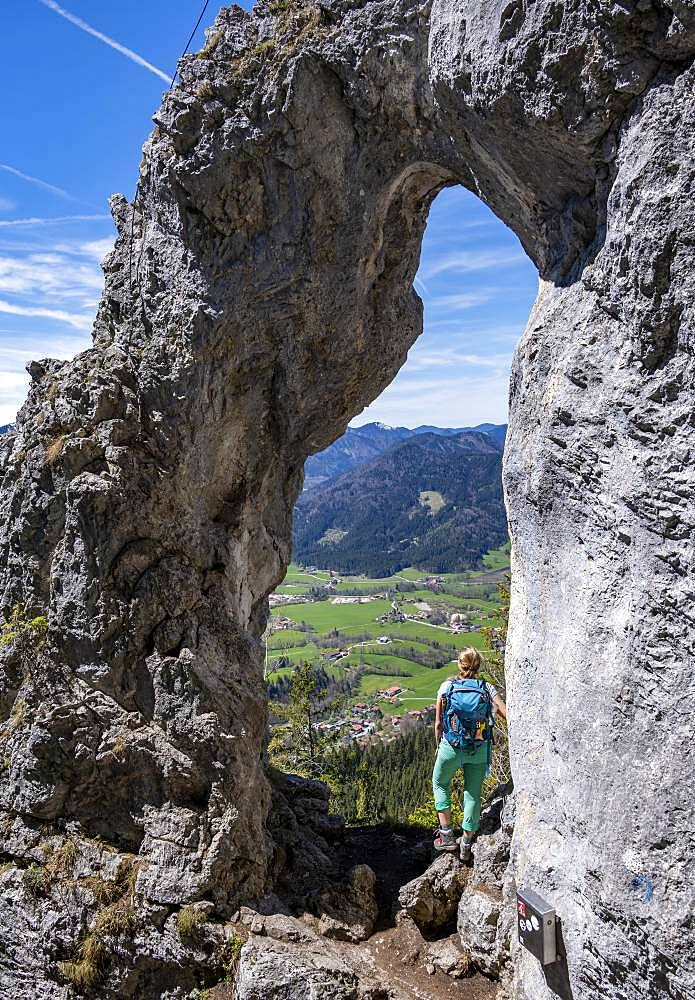 Hiker standing in the rock gate Breitensteinfensterl with view of high fog over the valley, hiking trail to Breitenstein, Fischbachau, Bavaria, Germany, Europe