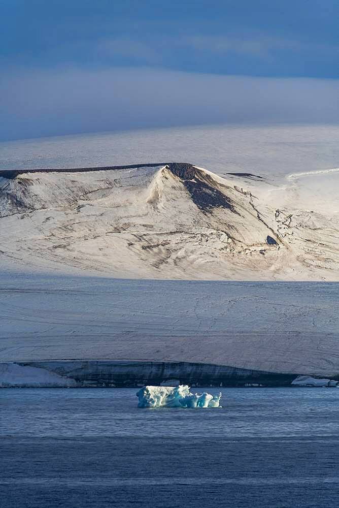 Iceberg floating before the flat table mountains covered with ice, Franz Josef Land archipelago, Russia, Europe