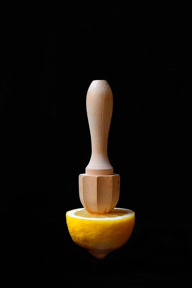 Lemon and lemon squeezer against a black background