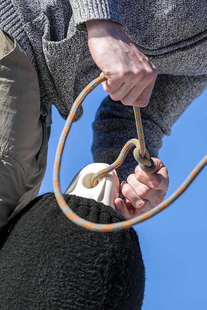 Young man tying a knot in a rope of a fender, sailors on a sailing catamaran, sailing trip, Dodecanese, Greece, Europe