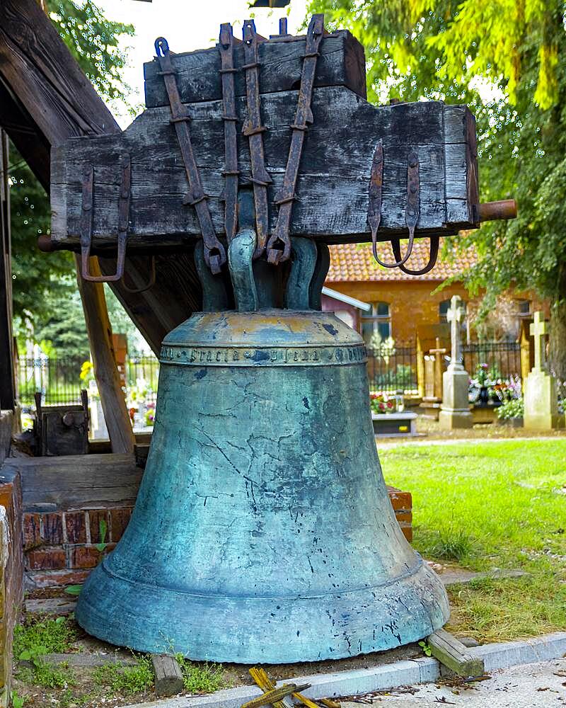 A belfry standing on the ground with four bells of different sizes in the village of Miloradz, Poland, Europe